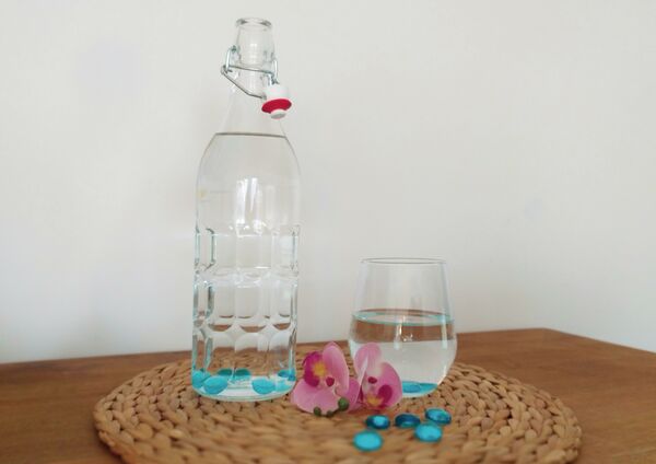 Flasche mit Glasnuggets und Glas auf Untersetzter dekoriert